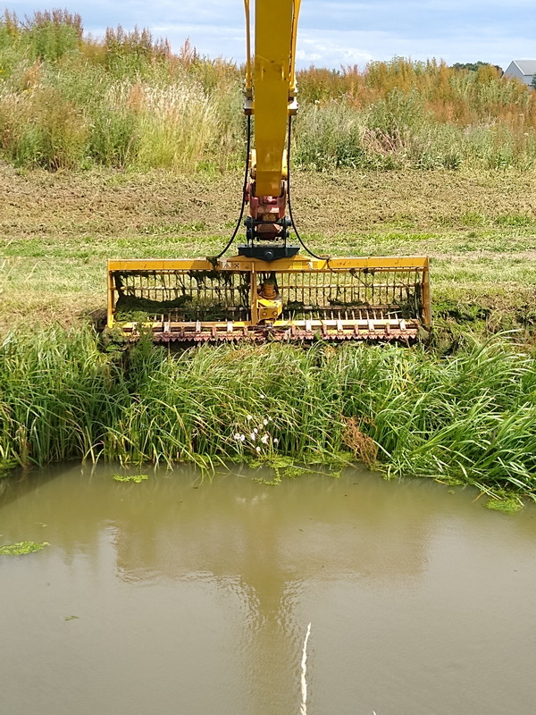 Machine dredging out weed from the side of a river